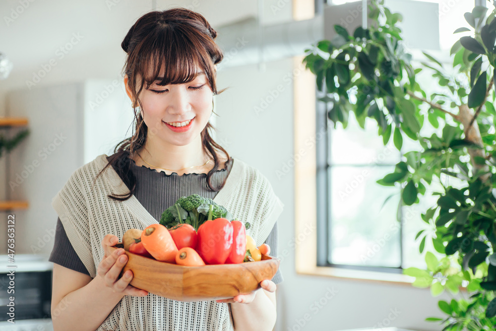キッチンの前に野菜を持つ女性
キッチンの前に野菜を持つ女性