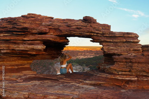 Back portrait of woman in natural red rock window with spectacular view