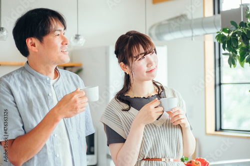 キッチンの前でコーヒーを飲む男女（夫婦）
