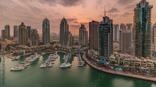 Sunrise over Dubai Marina luxury tourist district with skyscrapers and towers around canal aerial timelapse