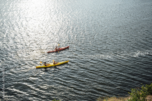 Two women and one man kayaking in the river at summer morning. Back view