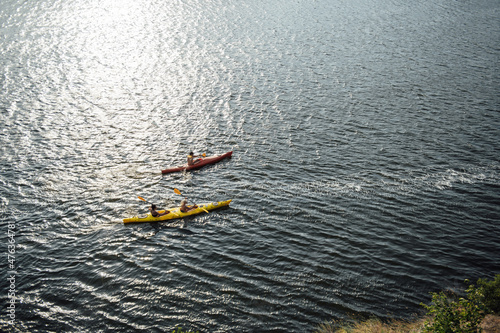 Two women and one man kayaking in the river at summer morning. Back view