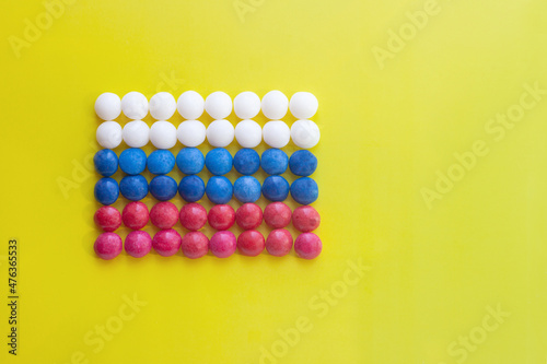 on a yellow background  the tricolor flag of Russia made of round sweets