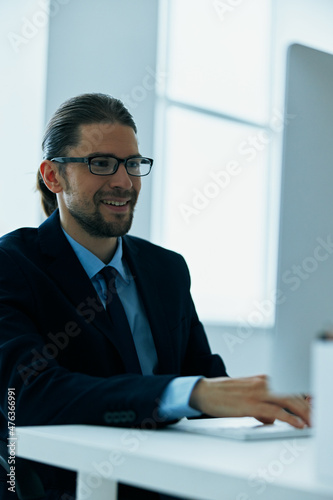 business man in a suit sitting at his desk tired in front of a computer