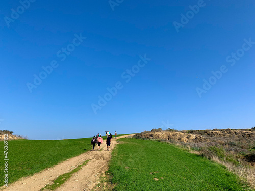 People silhouettes walking on the green field, blue sky, green grass, idyllic