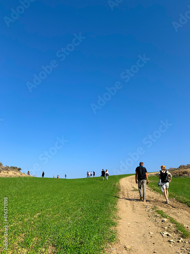 People silhouettes walking on the green field, blue sky, green grass, idyllic