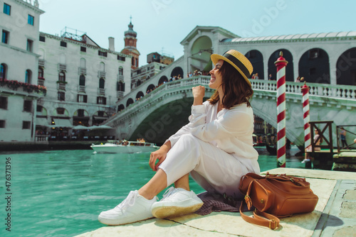 woman sitting near rialto bridge in venice italy looking at grand canal with gondolas