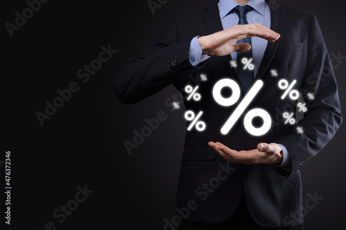 Fototapeta Naklejka Na Ścianę i Meble -  Male hand holding interest rate percent icon on blue background. Interest rate financial and mortgage rates concept.Banner with copy space