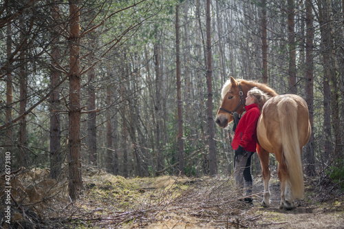 Woman walking with horse in forest