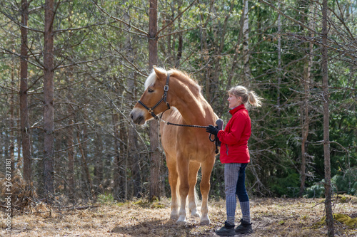 Woman walking with horse in forest