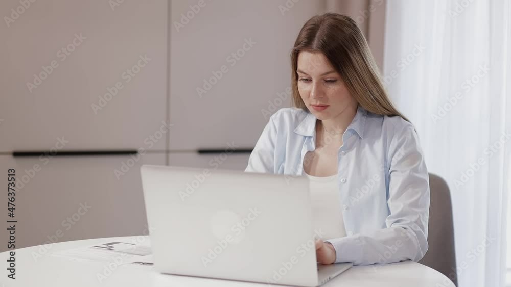 focused girl working from home sitting at a table with a laptop typing test messages, or learning remotely focused girl working from home sitting at a table with a laptop typing test messages, or learning remotely