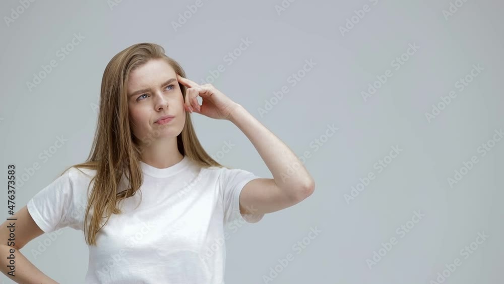 Smiling happy girl showing eureka gesture. young thinking pondering woman having an idea moment pointing her finger upwards on gray studio background Smiling happy girl showing eureka gesture. young thinking pondering woman having an idea moment pointing her finger upwards on gray studio background