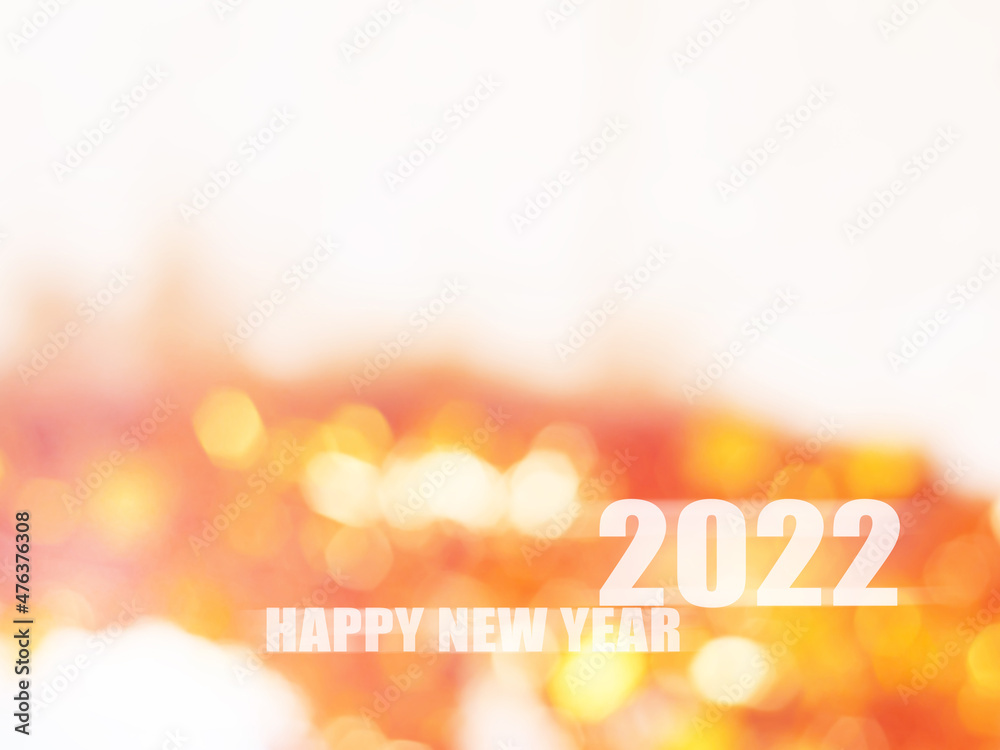 Sparkling orange and white tone bokeh with text Happy New Year 2022 for the holiday background. Sparkling orange and white tone bokeh with text Happy New Year 2022 for the holiday background.