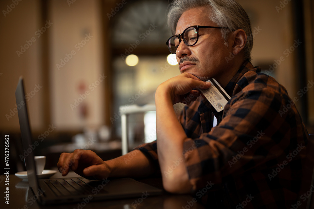 Man using laptop while sitting in cafe. Senior man holding credit card. Man using laptop while sitting in cafe. Senior man holding credit card.