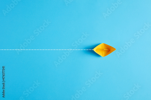 Fotografie, Obraz Yellow origami paper ship floats across the blue background