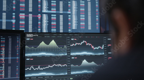Extreme close-up young adult man, crypto stock chart monitor background he is analyzing crypto coin