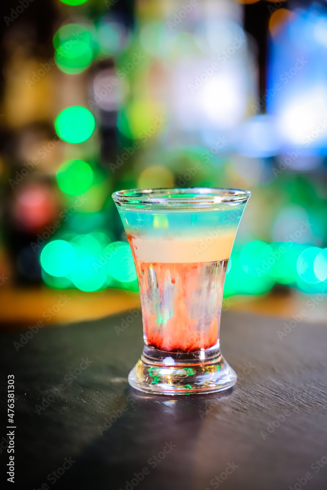 In the glass, the cocktail is brown-red, the top is white and the top is emerald, which is set on fire, the layers are not mixed.