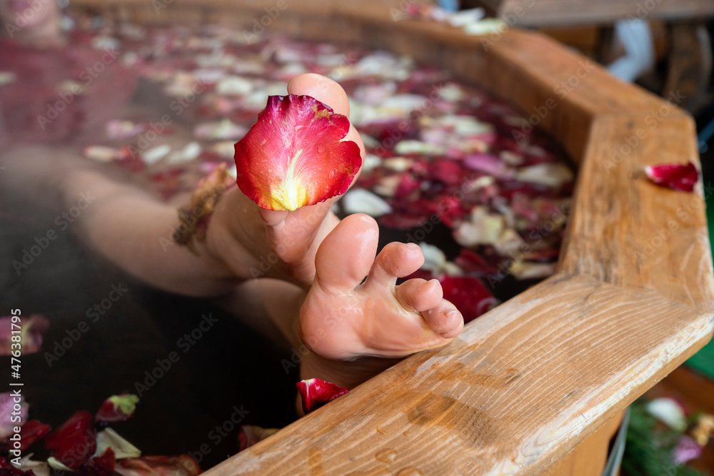 Beautiful young woman lying in a hot ofuro bath full of rose flowers