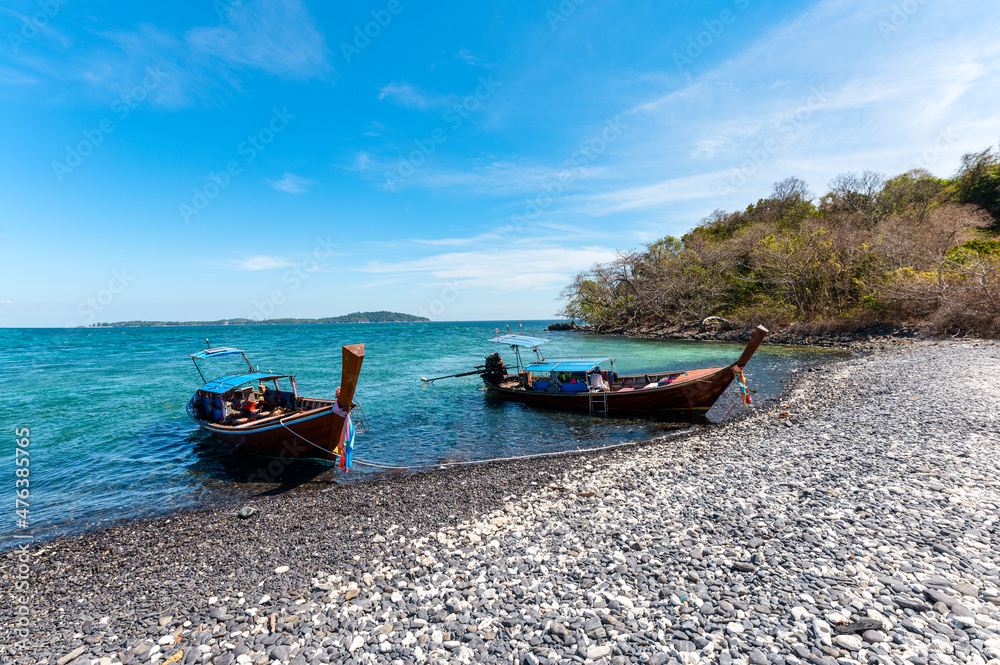 Long-tail boat anchored on black stone beach on sunny day at Koh Hin Ngam Long-tail boat anchored on black stone beach on sunny day at Koh Hin Ngam