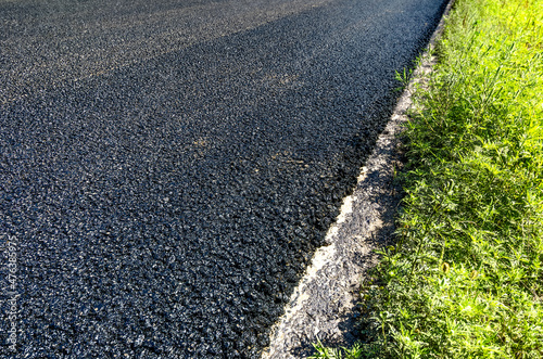 Layer of new asphalt with grass on road construction