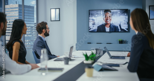 Video Conference Call in Office Boardroom Meeting Room: Black Female Executive Director Talks with Group of Entrepreneurs, Managers, Investors. Businesspeople Discuss e-Commerce Investment Strategy photo