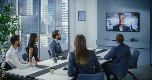 Video Conference Call in Office Meeting Room: Black Female Executive Talks with Group of Multi-Ethnic Digital Entrepreneurs, Managers, Investors. Businesspeople Discuss e-Commerce Investment Strategy photo