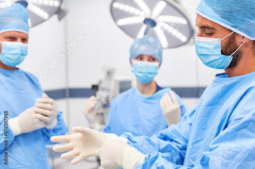 Gruppe Chirurgen zieht sich Latexhandschuhe an