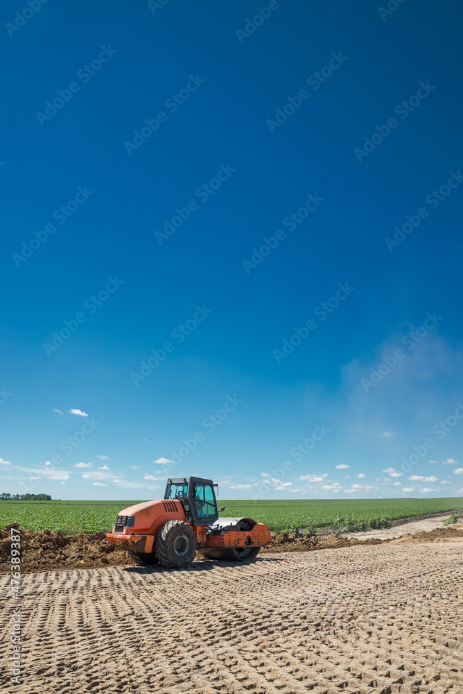 Obraz premium Earthwork during road construction. Orange tractor - Vibrating Roller.