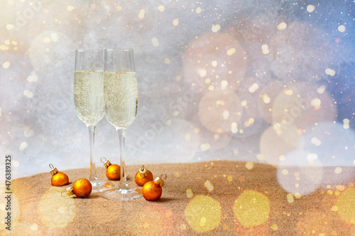 stylish  look of champagne flutes on the sand with New Year's toys under the wine glasses, and a lot of many glowing lights. waiting for the holiday