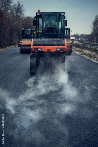 Hot asphalt smokes under the roller. Road construction.