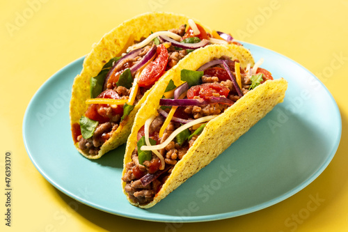 Traditional Mexican tacos with meat and vegetables on yellow background