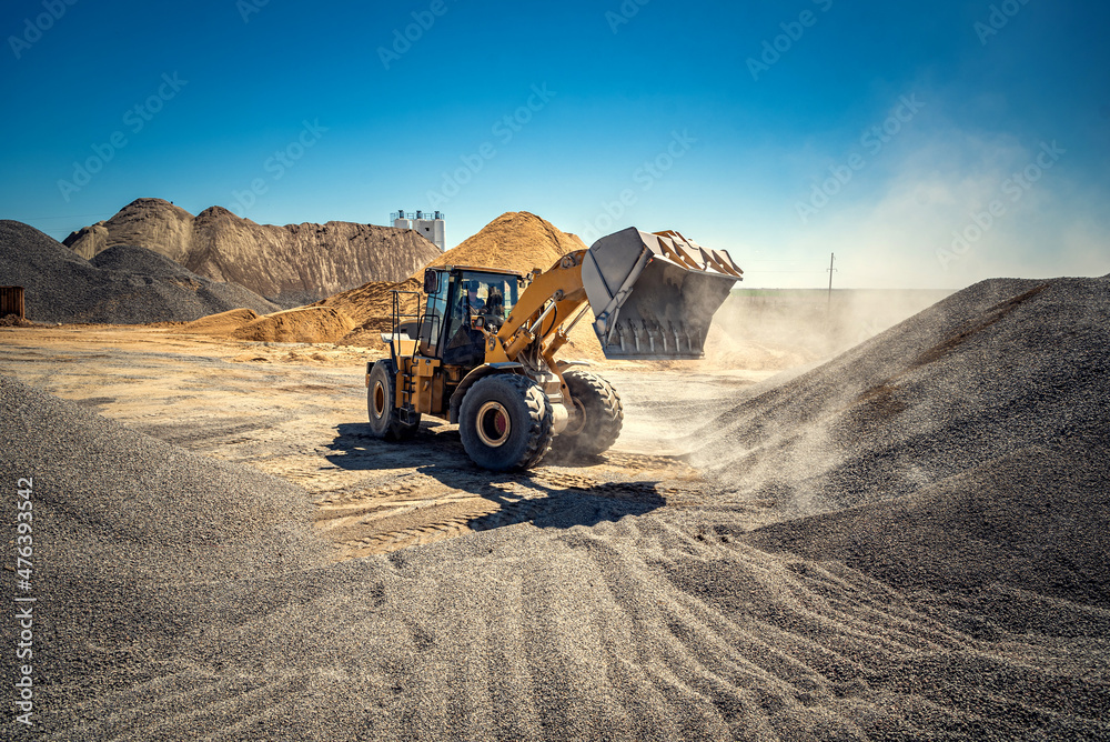 A large powerful loader overloads a pile of rubble in a concrete plant. A large powerful loader overloads a pile of rubble in a concrete plant.