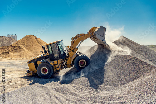 A large powerful loader overloads a pile of rubble in a concrete plant.