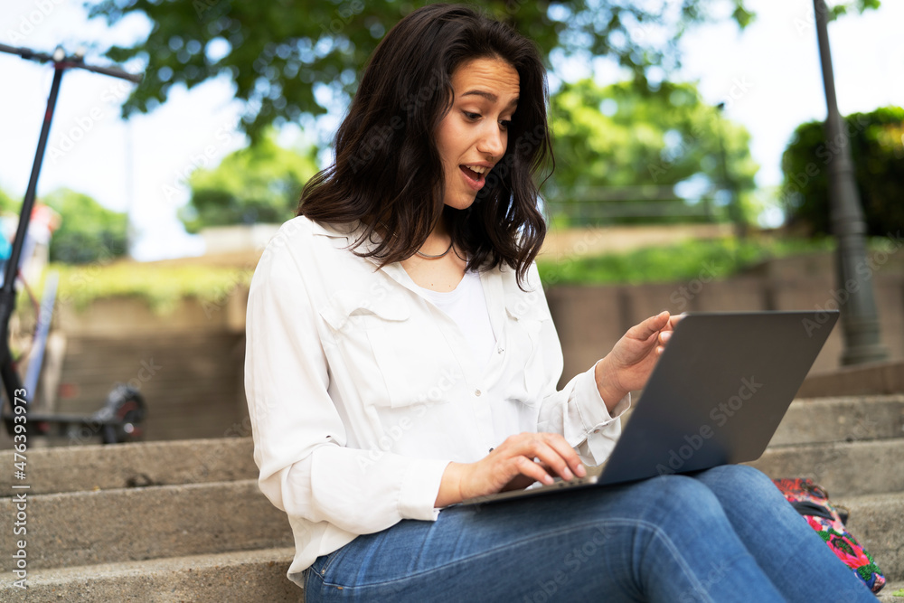 Young businesswoman sitting on steps outdoors and working on laptop. Beautiful girl learning in the park.. Young businesswoman sitting on steps outdoors and working on laptop. Beautiful girl learning in the park..