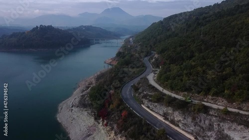 full hd aerial footage of following cars on a black asphalt lakeside road in the italian countryside