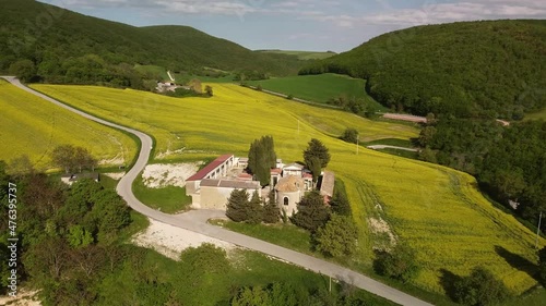 full hd aerial footage of a little graveyard in the middle of yellow flowers of rapeseed plants