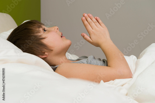 Kleiner Junge beim Abendgebet vor dem Schlafengehen im Bett