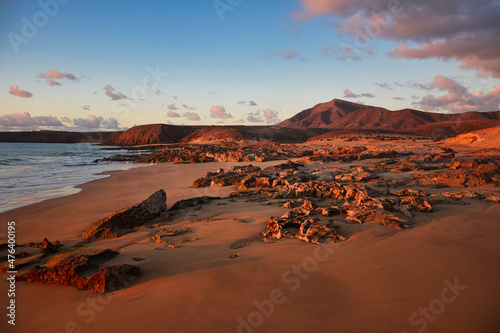 The west coast of Lanzarote at a beautiful sunset. A beach and a blue sky with some clouds. View to the mountain range Los Ajaches. Canary Islands, Spain.