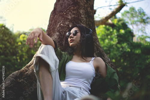 girl wearing sunglasses and headphone under the tree,lady listening music in the park,relax time