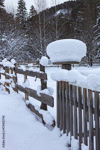 Snow caps on wooden fence posts.