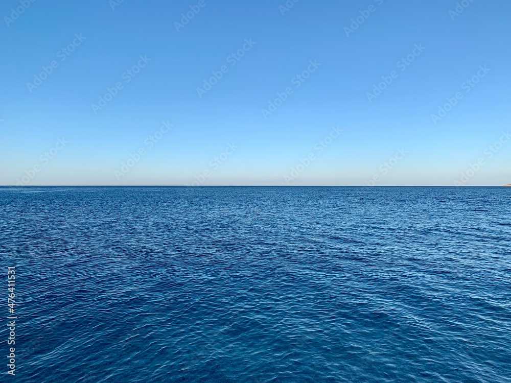 Fototapeta premium Blue sky and calm sea horizon. In the frame, half of the sky, half of the sea. Background texture: blue sky and clear water.