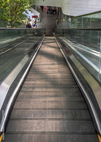 Bangkok, Thailand - Apr 16, 2021 : Modern escalator with people for facilities in a contemporary building. No focus, specifically. © num