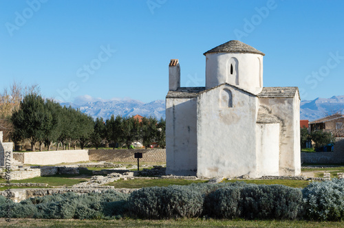 Nin, Croatia - Famous monument, church of Holy Cross and Velebit mountains in the background; preserved pre-romanesque architecture photo