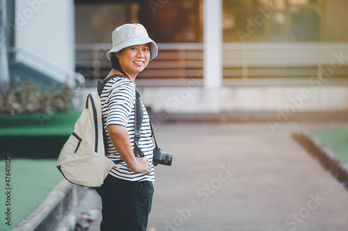 Asian woman traveling and taking pictures outdoors city streets, Asian female happy smiling backpacker using camera to take image on city walk streets, business travel concept