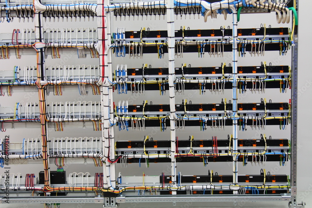 Installation of blocks and modules in an electrical panel with colored electrical wires.