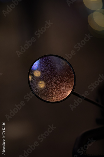 mirror view of a scooter in rainy conditions.
