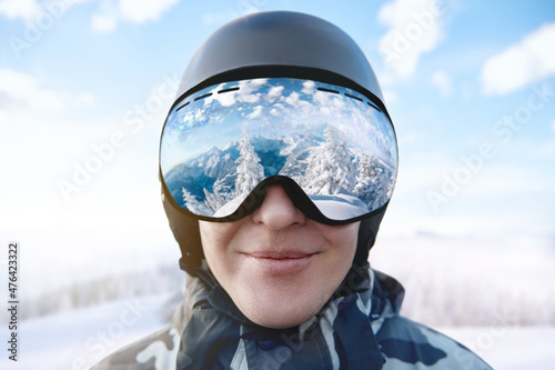 Ski Goggles With The Reflection Of Snowed Mountains. Man On The Background Blue Sky. Winter Sports.