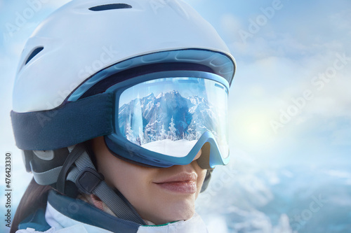 Portrait Of Young Woman At The Ski Resort On The Background Of Mountains And Blue Sky.A Mountain Range Reflected In The Ski Mask. Winter Sports.