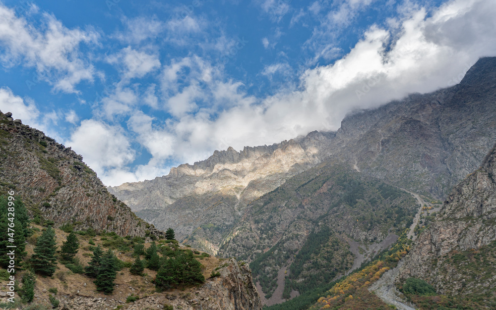 Mountain landscape panorama. A beautiful gorge on a sunny day, bright blue sky with fluffy white clouds.