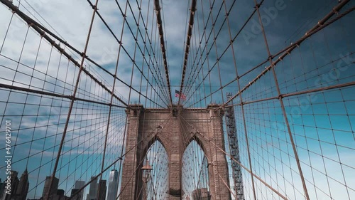 Hyper lapse time lapse of Brooklyn suspension bridge New York City with cloudy sky and United States flag